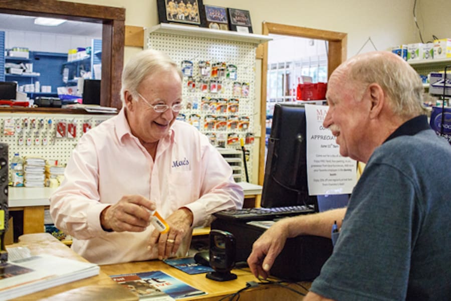Mac Pharmacy owner Mac Whiloit consults with Terry Dykeman about a prescription