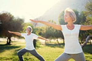 elderly couple doing yoga outside