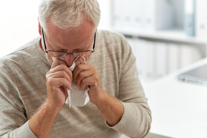 man sneezing into tissue