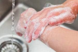 person thoroughly washing hands with soap and water