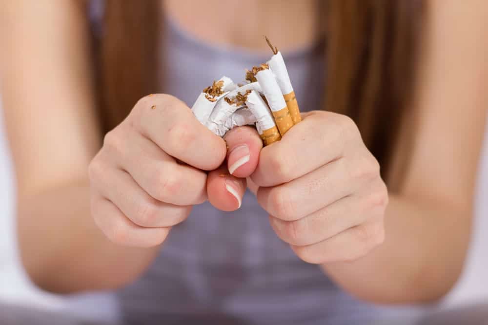 woman ripping cigarettes in half