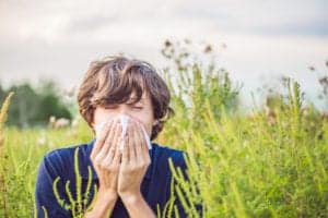 a man sneezing into a tissue outside