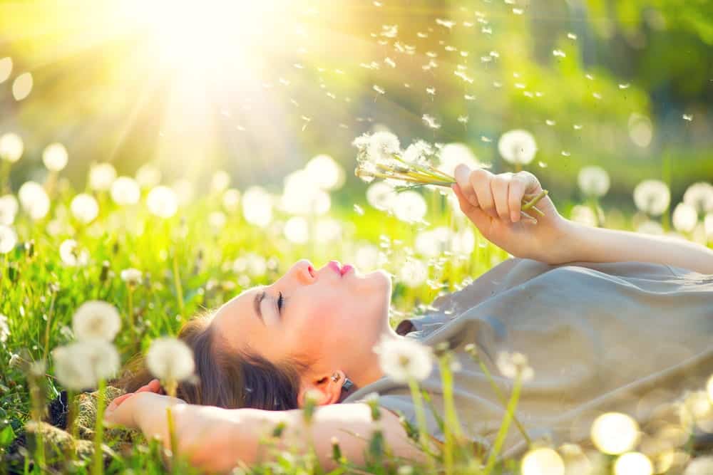 girl blowing on a flower outside