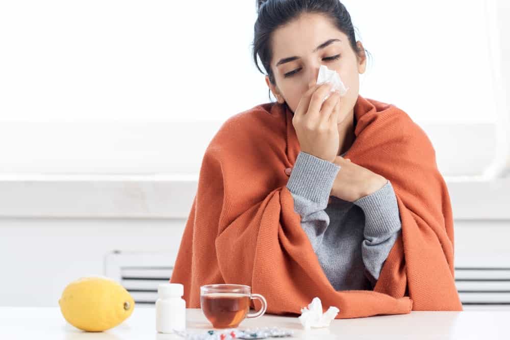 woman blowing nose since she has a cold