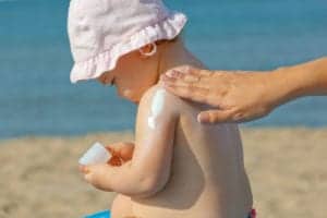 person putting sunscreen on baby