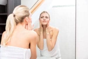 woman checking skin in mirror
