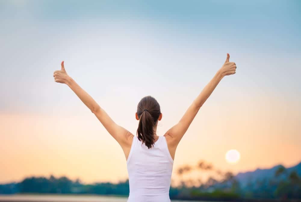 woman lifting arms with thumbs up