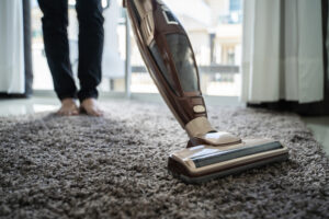 person vacuuming carpet in their home